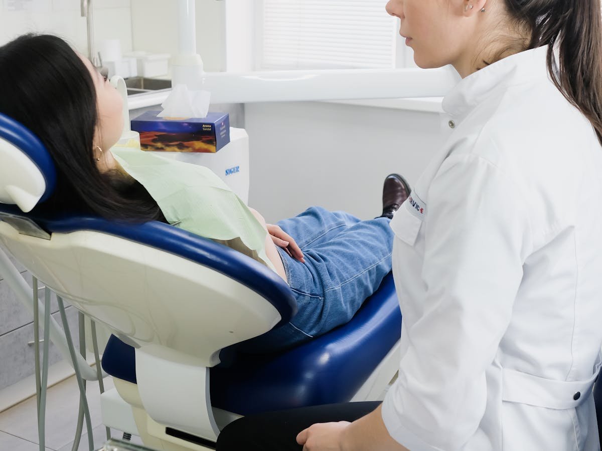 Dentista conversando com paciente em consultório odontológico